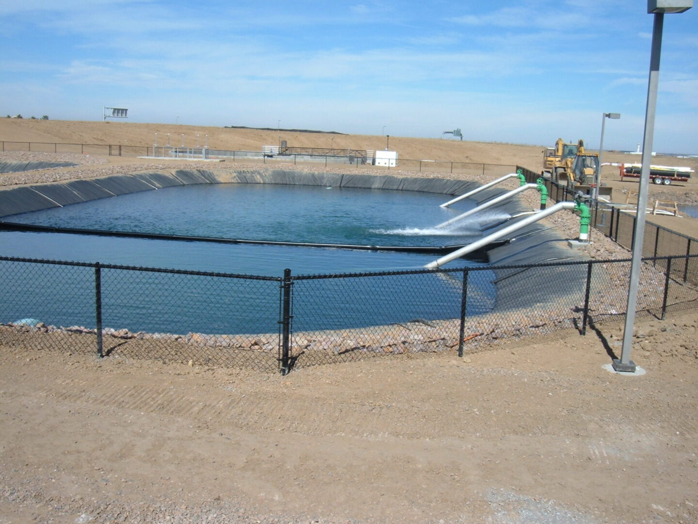 A large pool of water near a dirt field.