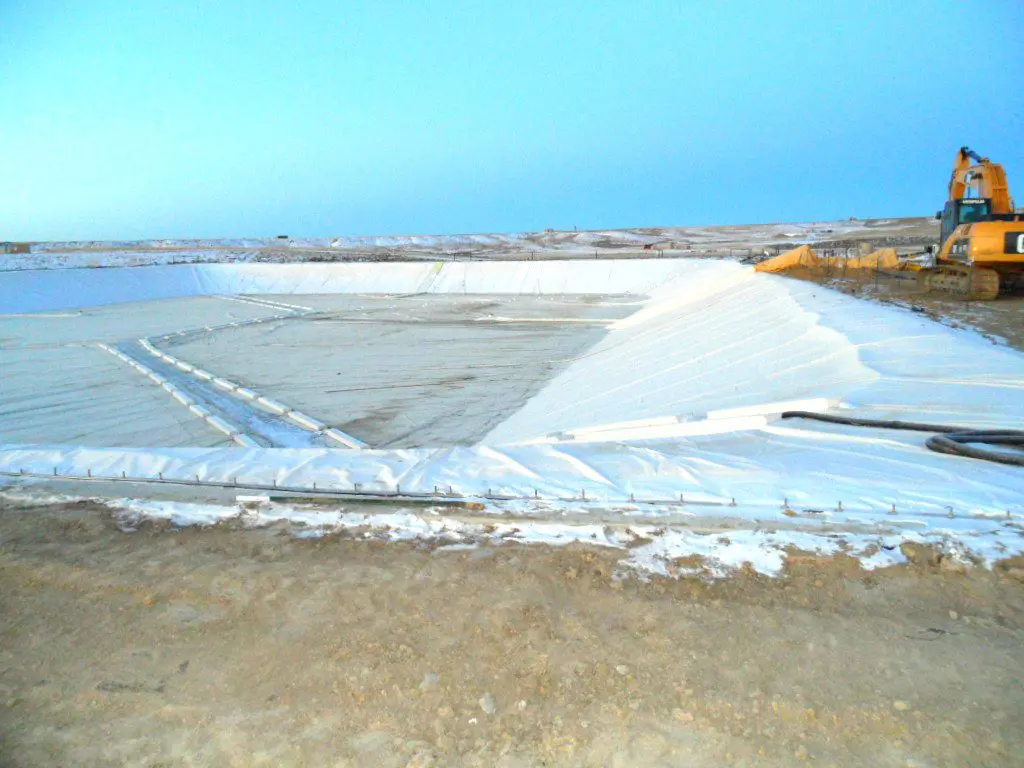 A large field of snow on the side of a river.