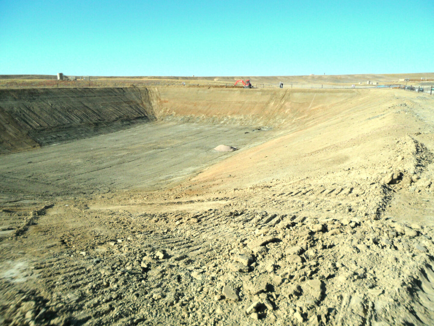 A dirt field with a large open pit in the background.