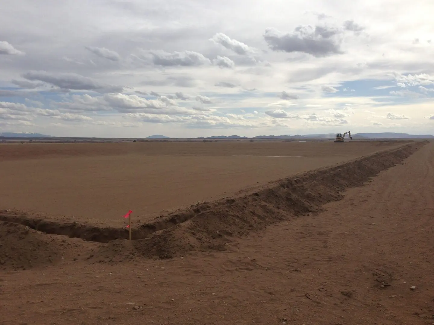A dirt field with a red flag in the middle of it.