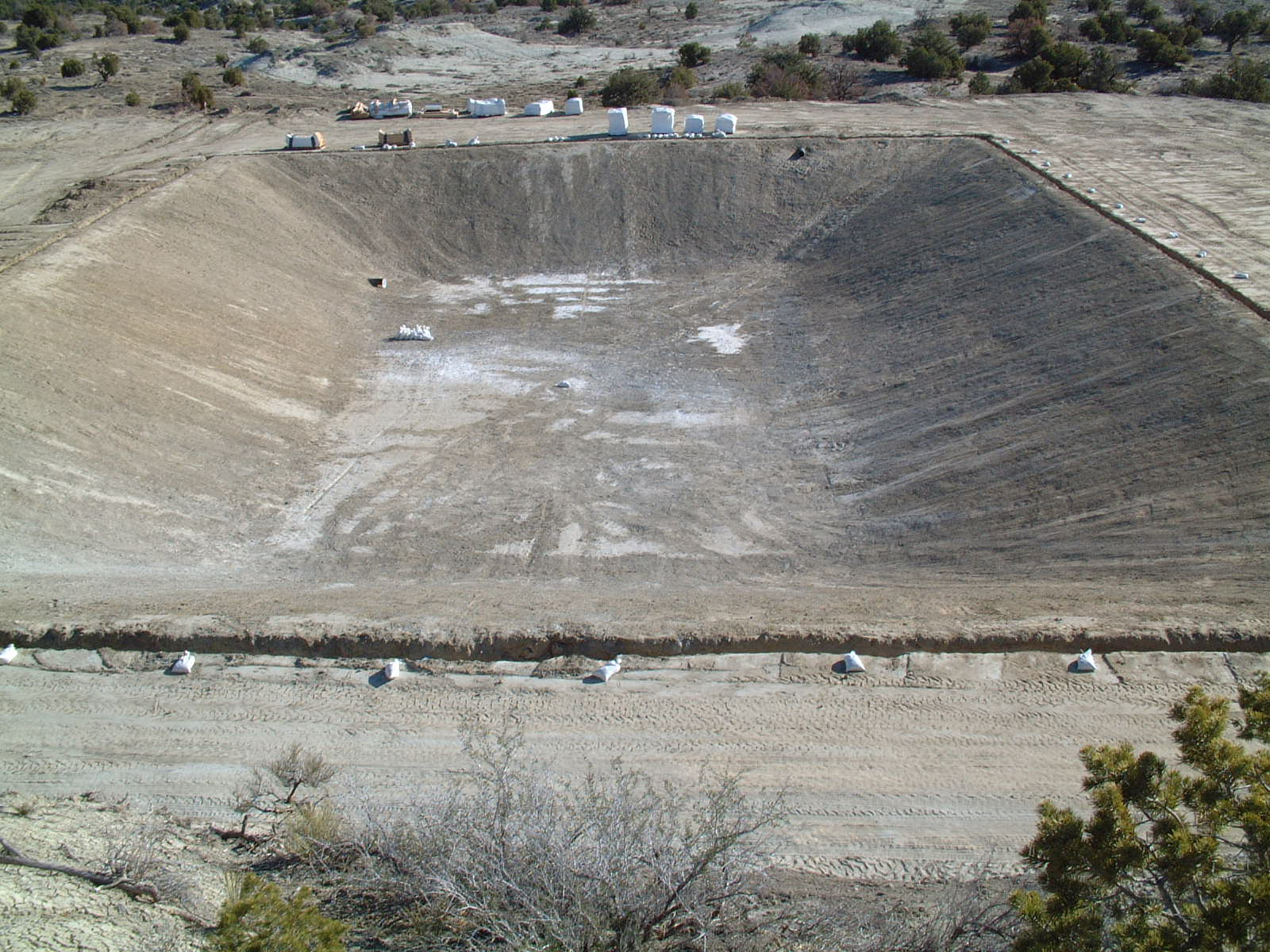 A large dirt pit with cars parked on top of it.