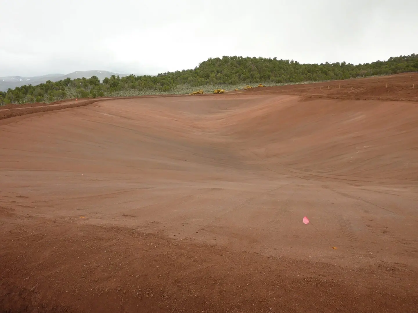 A red ball is in the middle of a dirt field.