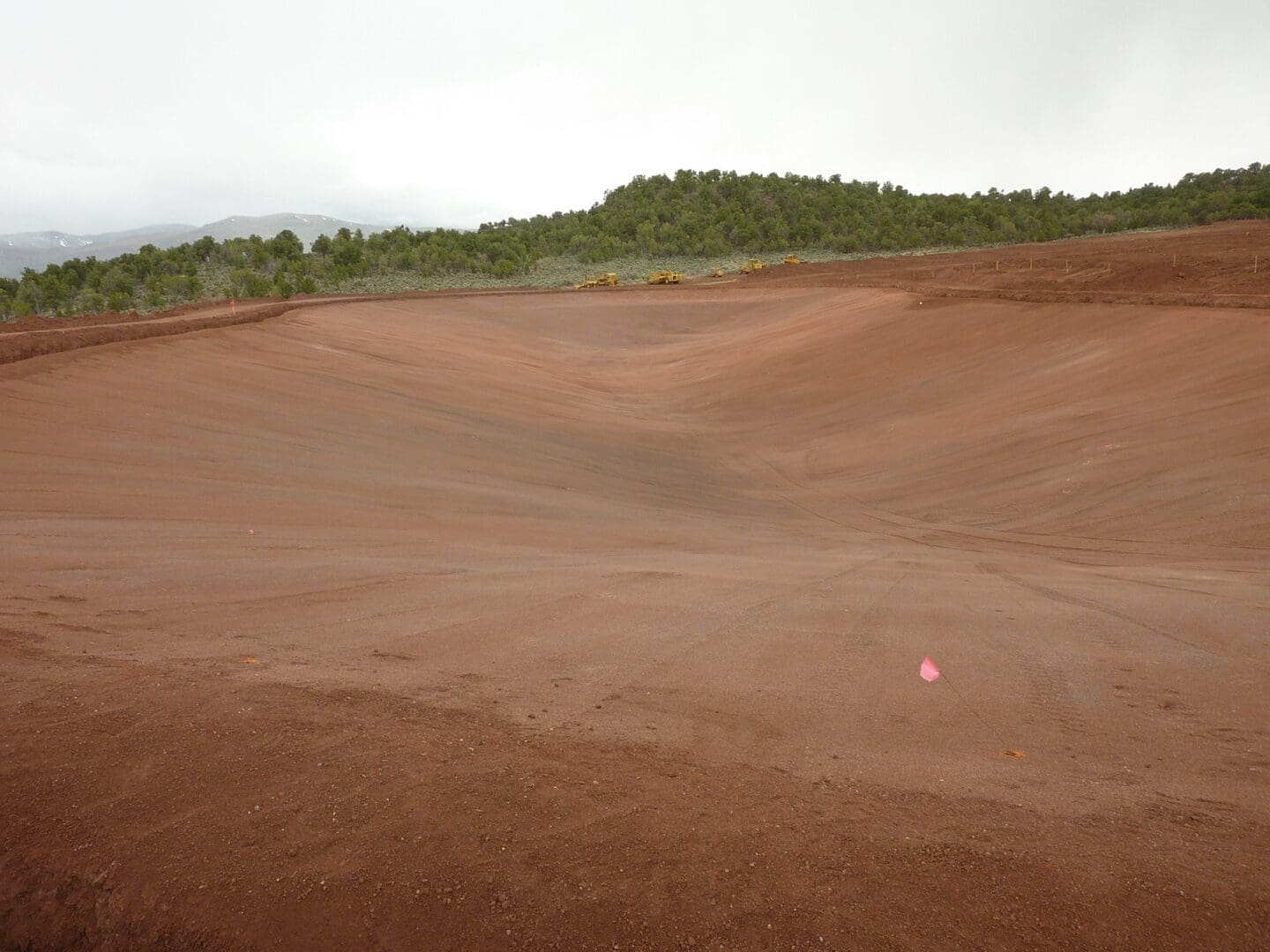 A red ball is in the middle of a dirt field.