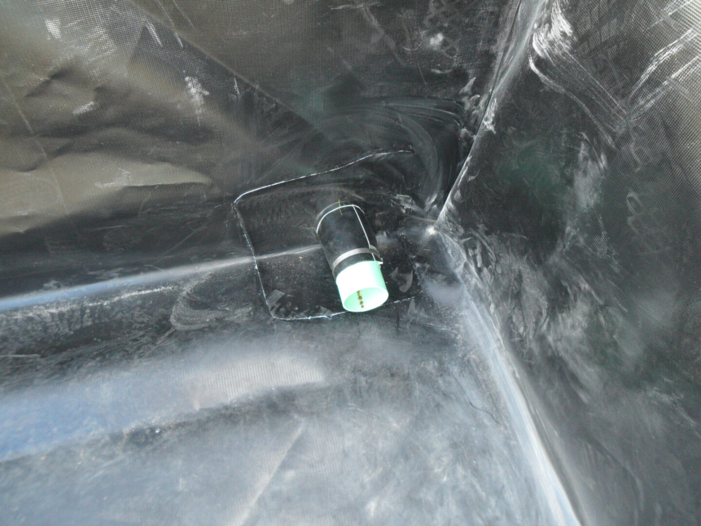 A bottle of liquid is sitting in the middle of a black plastic bag.
