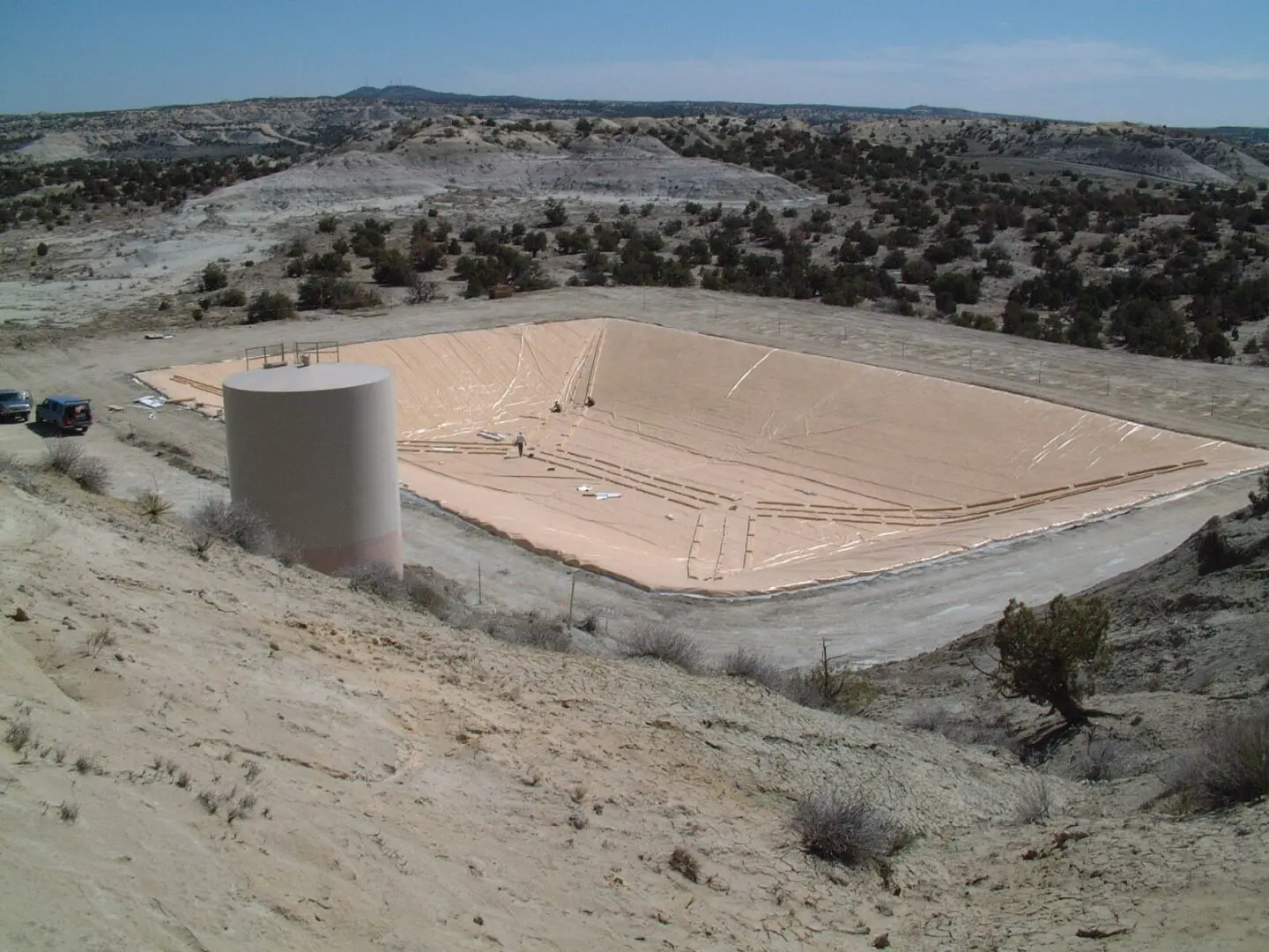 A large sand pit with a water tank in the middle of it.