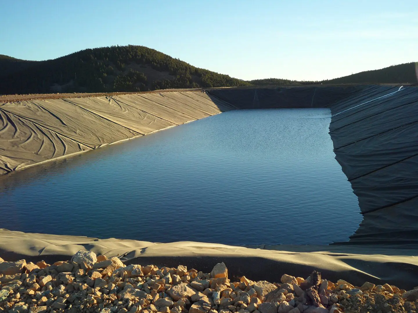 A body of water with rocks and hills in the background.