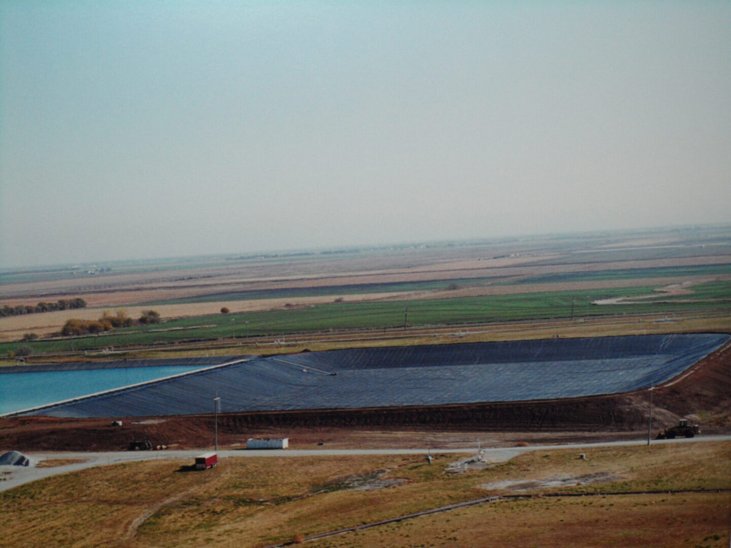 A large field with a truck driving down the road.