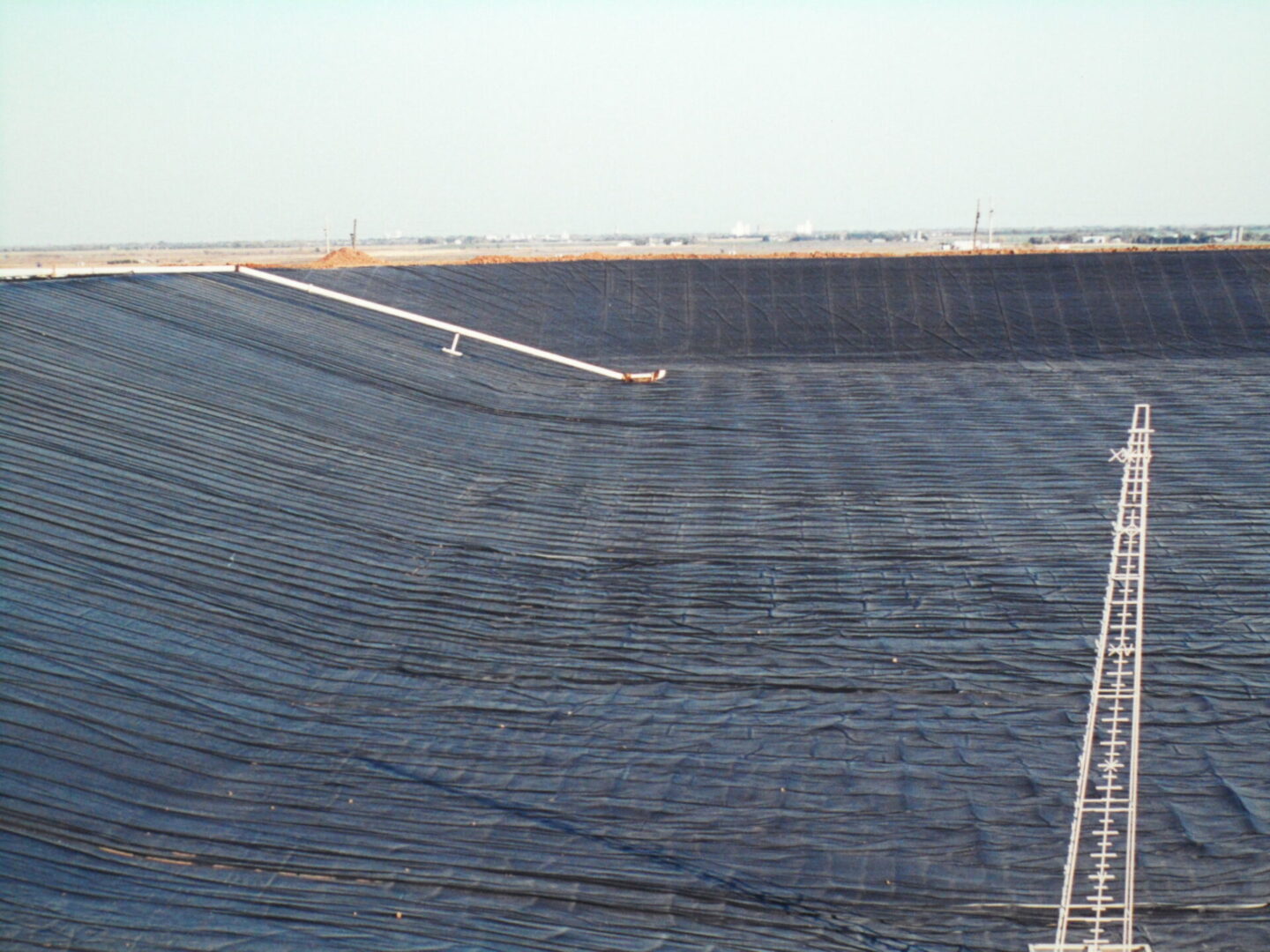 A large area of water with black tarps covering the ground.