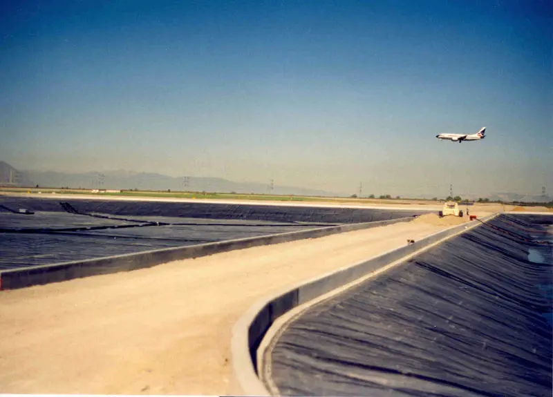 A large runway with an airplane flying overhead.