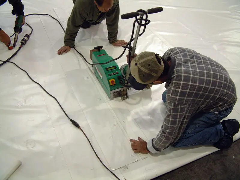 Two men working on a sheet of plastic.