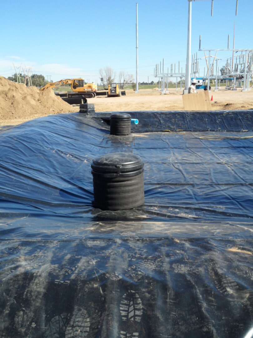 A black tarp covering the ground with a large tank.