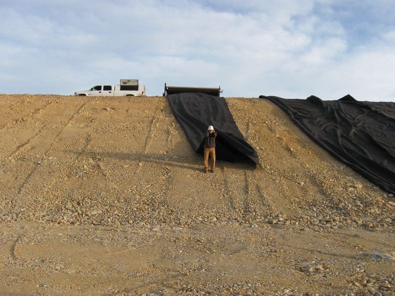 A man standing on top of a hill near a truck.